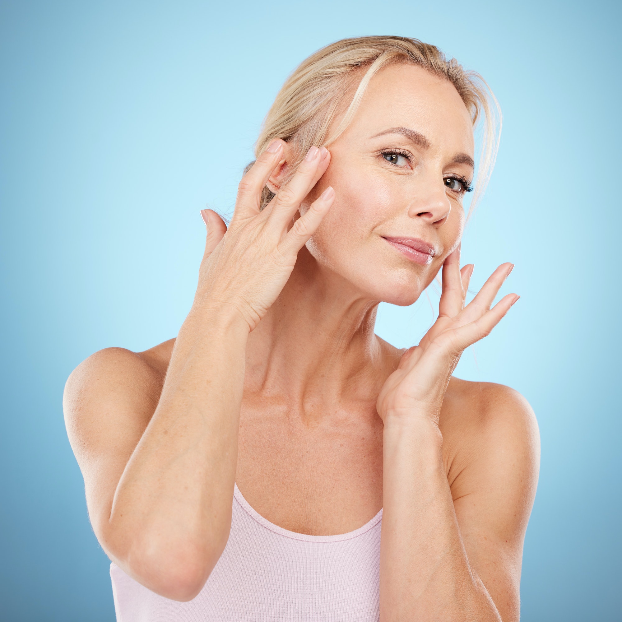 Woman touch face for beauty, skincare and blue background for wellness, cosmetics and salon spa res